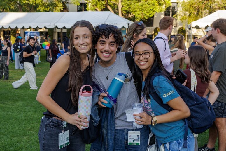 two female students, one male, smiling at welcome back bash