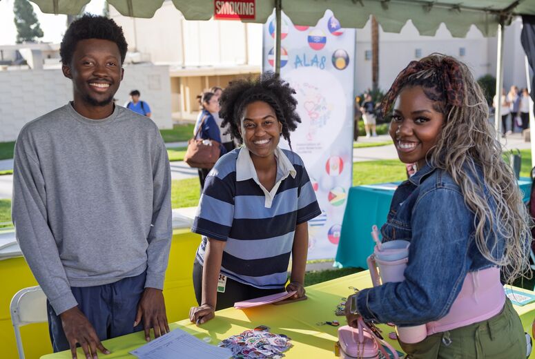three Black students smiling at the camera at welcome back bash