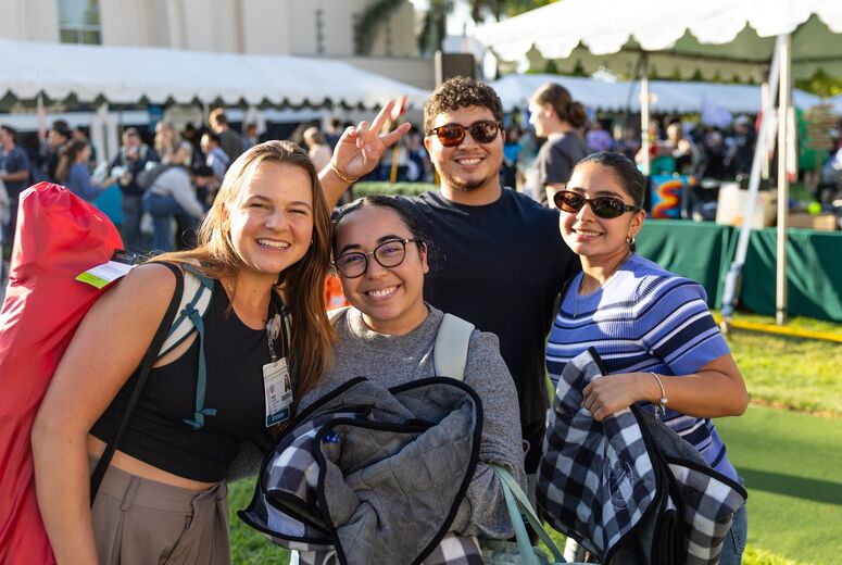 four students outside smiling at welcome back bash
