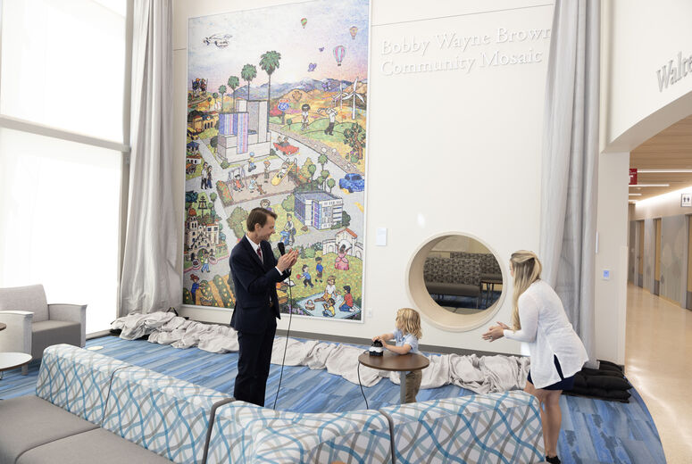 young boy pushes button to unveil mosaic mural