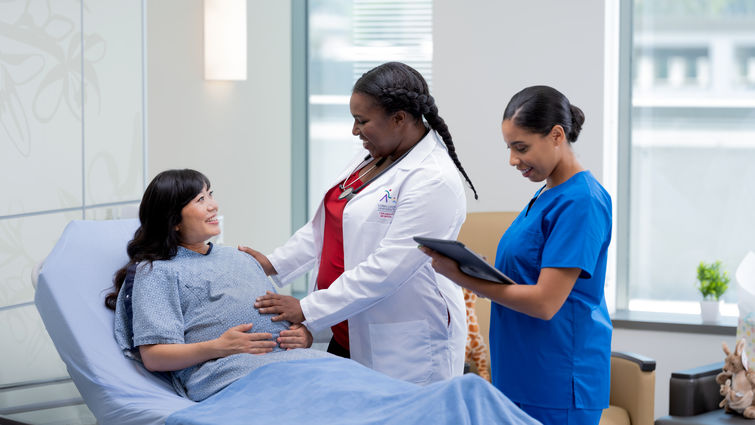 pregnant mom on bed being examined by female doctor and nurse