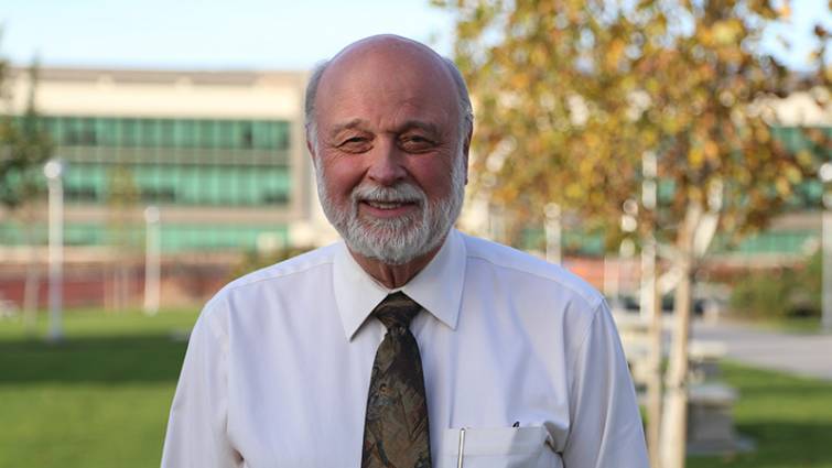 Man smiles in photograph on campus