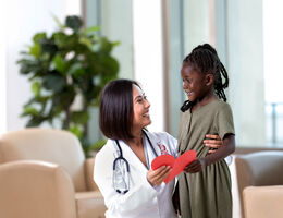 Picture of doctor hugging child while holding a cut-out of a heart 