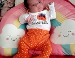 A mom, her baby, and their family's story of hope and healing after COVID-19 baby laying on rainbow pillow