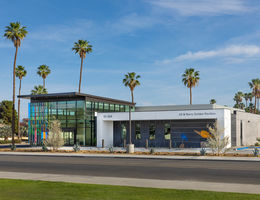 wide shot of concrete and dichroic glass building framed by beautiful blue sky and picturesque palm trees