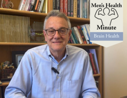 A white, male doctor sits in front of a bookshelf with a blue shirt on. Text on the screen says 'Men's Health Minute, Brain Health'