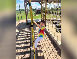 young asian girl climbing on ropes at the park