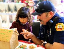 Gingerbread Village 2018 Firefighter helps young girl decorate gingerbread house