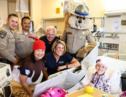 LLU Children’s Hospital patients treated to ice cream social by Stater Bros. Charities visitors pose by bedside of young female patient for photo