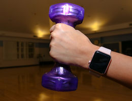 caucasian hand holding small purple dumbbell
