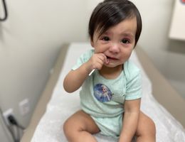 female toddler sitting on doctor's exam table clearly upset
