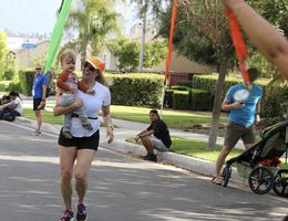 Woman crossing finish line with baby on her hip