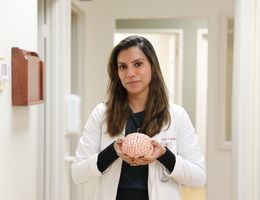 Brunette female physician holds the model of a brain in a hospital hallway