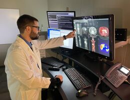 A man is looking at a computer screen of a human body scan