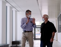 a man is talking with another man as they are walking within a building