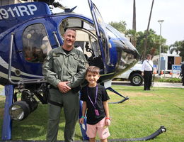 Police officer next to young boy in front of a helicopter
