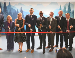 hospital leaders pose while cutting ribbon