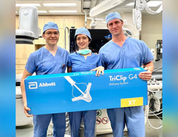 Male, female, male doctor stand smiling in operating room holding TriClip box