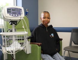 Sickle cell disease patient sitting in green chair for infusion treatment