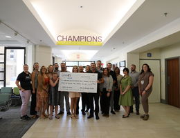 Corky's and Loma Linda University Children's Hospital staff stand together, all smiles, during a check presentation supporting the hospital's mission to provide exceptional care to young patients.