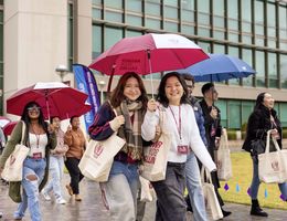 a group pf young adults holding umbrellas walking in the rain