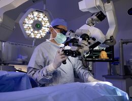 A doctor looks through microscope during surgery 