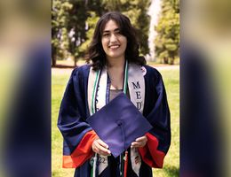 Zoe Gomez poses in a graduation gown
