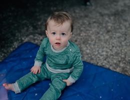 one year old baby Oliver Bonds sits on blue blanket and looks at the camera