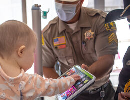 baby plays with toy held by sheriff's deputy