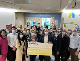 Walter’s Children’s Charity Classic members present a check to Loma Linda University Children’s Hospital administration and staff Group of people in a hospital hallway during a check presentation