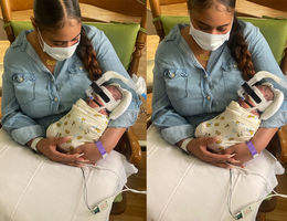 Chaquan May visits Gi'arri regularly in the NICU. The team hopes Gi'arri will be discharged by the end of May. mom sits in rocking chair wearing mask, cradling her baby in her arms hooked up to wires