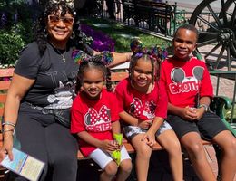Gaylyn sitting on bench at Disneyland with her three grandchildren. Two girls, one boy