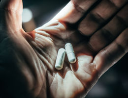 Hands holding pills in dramatic light. - stock photo