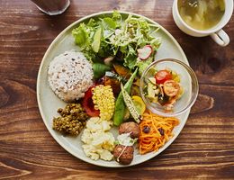 Vegan plate lunch with organic vegetables on a wooden table with a mug of green tea