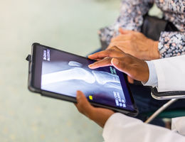 Close-up of a doctor sharing the treatment from the x-ray scan on digital tablet with a patient