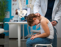 Pediatrician doing development medical exam with little girl, checking spine