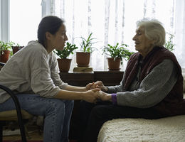 Young woman holding old woman's hands during conversation
