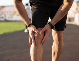 Unrecognizable sports man injures his knee while jogging 
