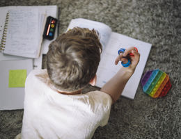 Directly above view of boy fidgeting with ring toys while doing homework at home