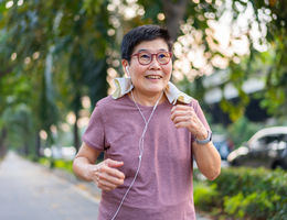 A senior woman wearing earphones while walking for exercise.