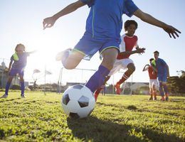 Close up of boy wearing a blue soccer uniform kicking soccer ball 