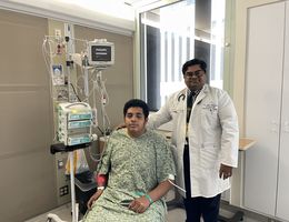 Dr. Jain stands next to hemophilia patient Edgar
