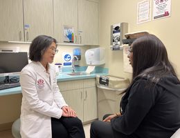 Sharon Lum, MD, MBA, chair of the LLUH Department of Surgery speaks with a breast cancer patient in a clinic room.