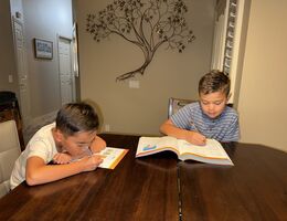 Two young boys sitting at a table working on work books