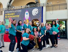 Group of people outside in matching teal t-shirts smiling at the camera