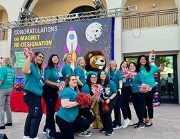 Group of people outside in matching teal t-shirts smiling at the camera