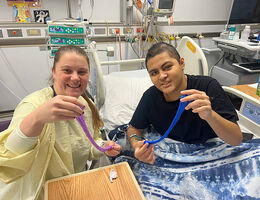 Child life specialist and patient play with slime they made at the patient bedside