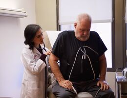 A doctor uses her stethoscope to listen to a patient's heart 