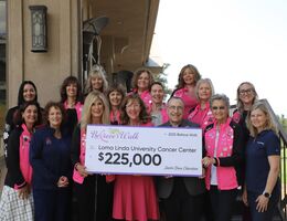 A group of people standing together on steps holding a check 