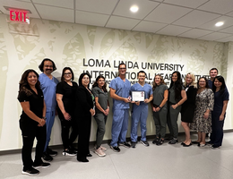 Care team members of the Structural and Valvular Heart Disease program at Loma Linda University Medical Center gather around and pose with their certification from the American College of Cardiology for transcatheter valve care in adult cardiac patients.